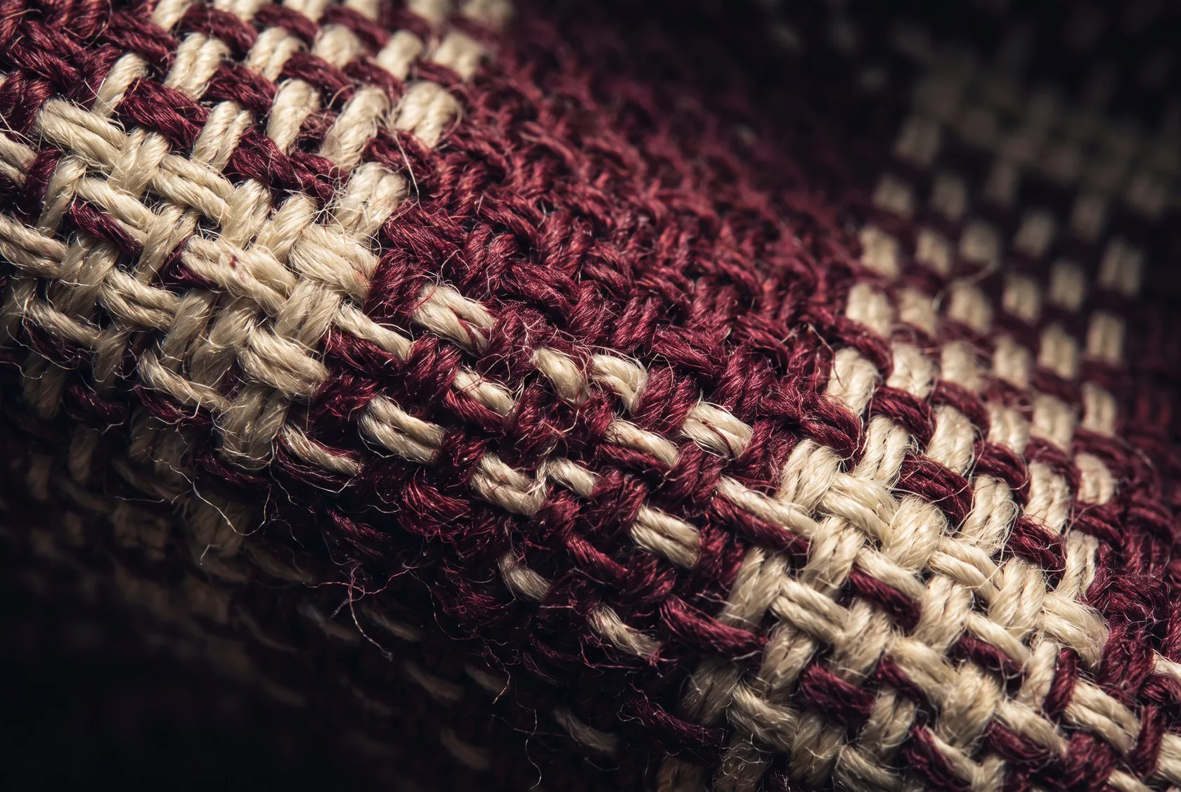 Macro detail of interwoven burgundy and ivory fabric threads