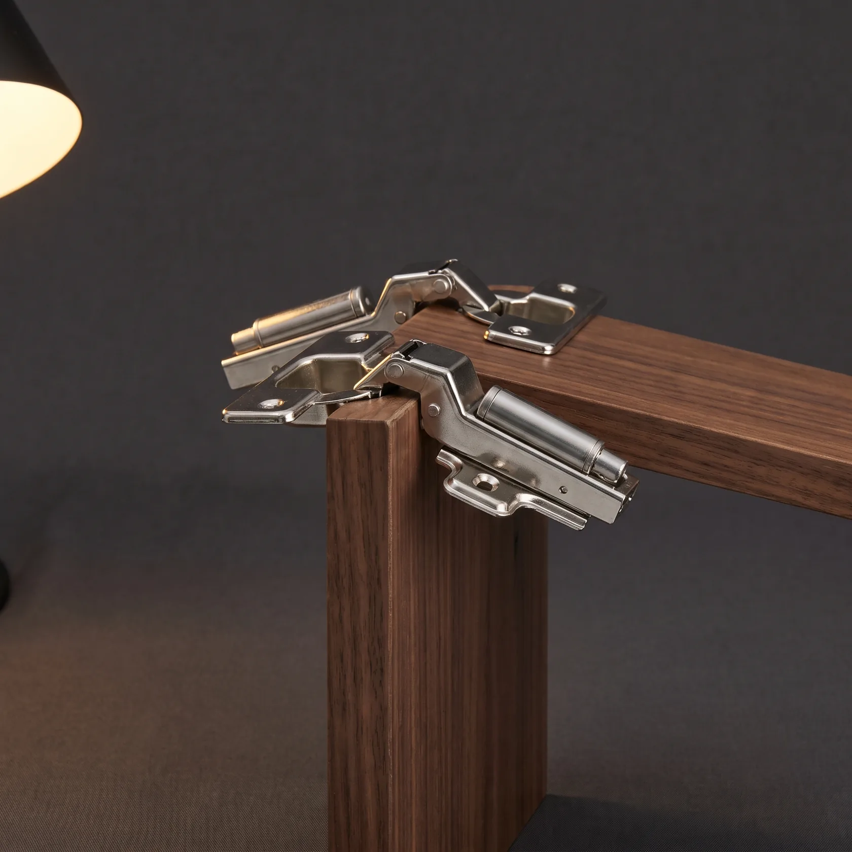 Chrome soft-close cabinet hinges mounted on a dark walnut cabinet edge